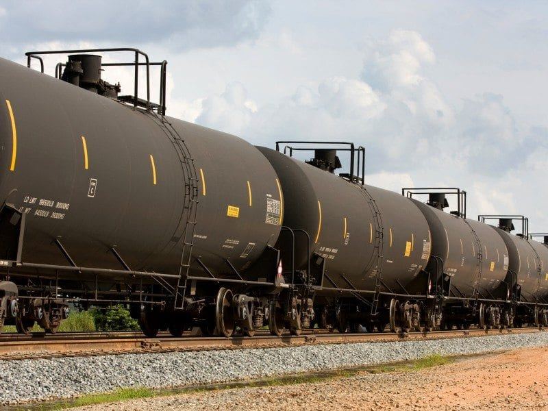 Rail tanker cars moving through an industrial logistics corridor